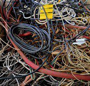 A tangled mess of various cables and wires with a yellow plug.