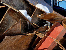 A white pigeon perched on a rusty metal structure near some wooden planks.